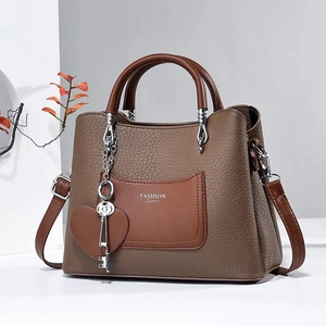 Close-up of brown faux leather bag with heart and key charms and FASHION Queen print