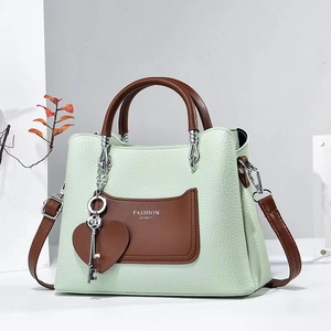 Detail of mint green PU leather handbag featuring lychee texture and heart charm
