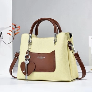 Detail of yellow pebbled handbag featuring brown pocket and Fashion Queen lettering