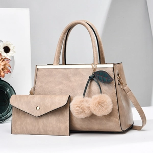 Détail du sac à main marron clair avec barre métallique et pompon décoratif doux