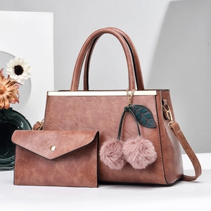 Détail d'un ensemble de sacs en cuir PU marron avec pompon cerise et attaches dorées