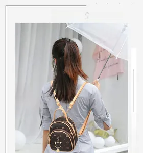 Detail of dark brown monogram mini backpack with cat charm and dual zipper layers