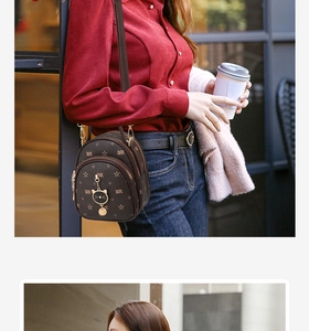 Detail of dark brown mini backpack with star monogram and cat charm on red shirt