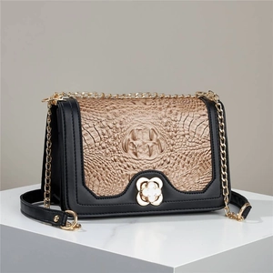 Close-up of khaki crocodile pattern crossbody bag with gold flower buckle and chain