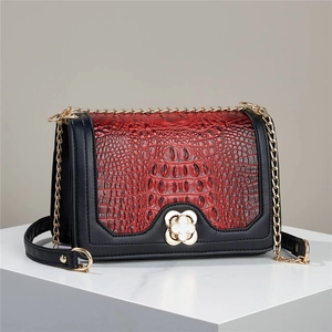 Detail of red crocodile texture bag with gold clover clasp and black leather trim