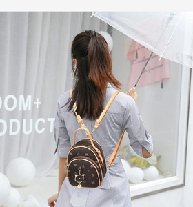 Brown mini backpack featuring star patterns and cat charm shown on model's back