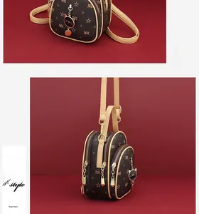 Detail of dark brown mini backpack featuring MK pattern and gold cat charm with strap