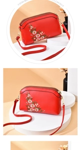 Close-up of red PU leather bag with floral embroidery and gold zip compartments