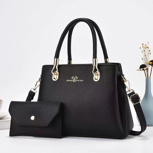 Close-up of black litchi pattern leather tote bag set with golden hardware and bow detail