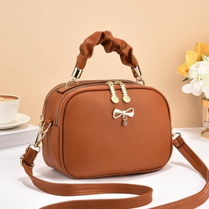 Brown lychee leather crossbody bag with scrunchie handle and gold bow charm detail