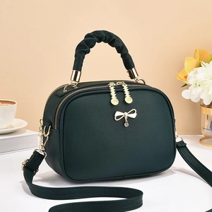 Detail of green lychee leather handbag with ruched handle and golden bow charm