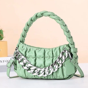 Detail of green quilted handbag featuring a chunky silver chain and woven handle