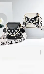 Détail du sac bandoulière tissé avec chaîne en perles et sangle graffiti sur socle