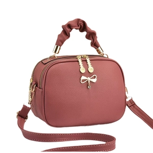 Pink lychee texture crossbody bag with gold bow detail and pleated handle on white background