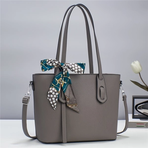Detail of grey cross-grain leather tote bag with decorative dotted silk scarf and strap