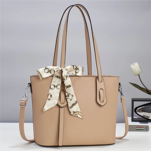 Detail of beige tote bag in cross-grain leather with decorative silk scarf and long strap