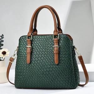 Detail of dark green woven texture tote bag with brown leather handles and gold hardware