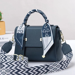 Detail of navy blue pebble leather handbag with silk scarf handle and geometric strap