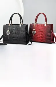 Detail of crocodile texture tote bag with heart charm and pearl accent on white background