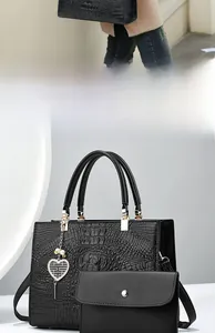 Close-up of black crocodile embossed tote bag with gold hardware and heart pearl pendant