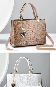 Detail of large tote bags in khaki and white featuring crocodile texture and heart charms