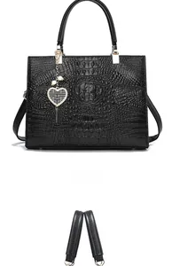 Close-up of black crocodile pattern tote bag featuring a heart charm with bead details