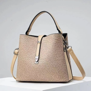 Detailed shot of beige lace bucket bag featuring leather trim and metal clasp closure