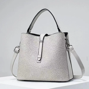 Detail view of white floral lace handbag with silver buckle and adjustable strap