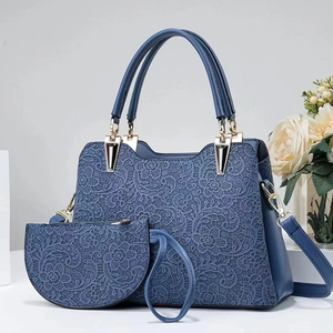 Close-up of blue lace embroidery detail on a large handbag with golden metal hardware