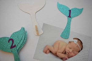 Close-up of teal glitter mermaid tail photo clips for baby 1st birthday banner