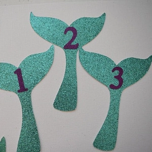 Glittery mermaid tail photo banner with numbers one two and three for first birthday party