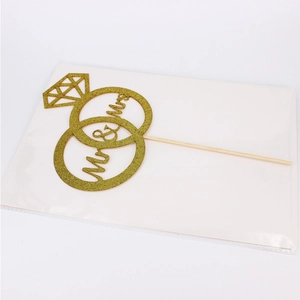 Close-up of gold glitter Mr & Mrs wedding cake topper with double ring and diamond design