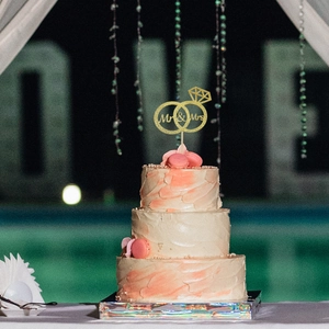 Close-up of golden glitter Mr & Mrs cake topper with ring detail on white tiered cake
