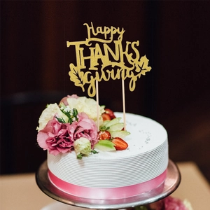 Gros plan d'un topper de gâteau doré pailleté Happy Thanksgiving avec feuille d'érable décor
