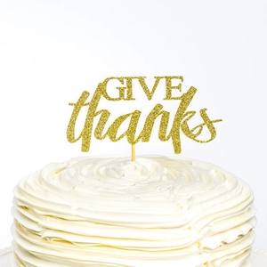 Gros plan d'un cake topper GIVE thanks doré pailleté sur un gâteau à la crème blanc