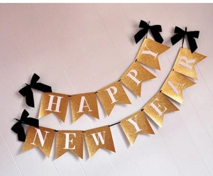 Détail d'une bannière Happy New Year dorée à paillettes avec des nœuds en velours noir