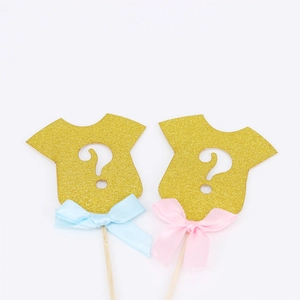 Gold glitter baby onesie cake toppers with pink and blue bows for gender reveal party