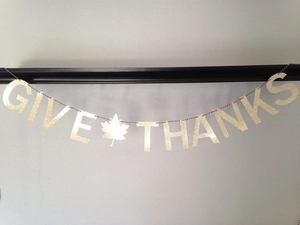 Close-up of glittery GIVE THANKS banner with gold maple leaf for Thanksgiving decor