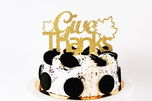 Macro shot of gold glitter Give Thanks cake topper with maple leaves for Thanksgiving