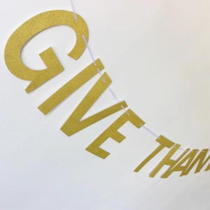 Close-up of golden glitter GIVE THANKS banner letters for Thanksgiving party decoration