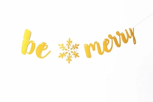 Detail of glittery gold 'be merry' banner with a decorative white snowflake ornament