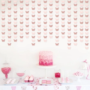 Pink and rose gold glitter butterfly garland hanging over a romantic dessert table setting