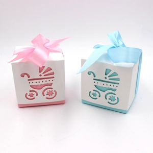 Detail view of pink and blue hollow-out baby stroller candy boxes with satin bows