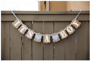 Detail of IT'S A BOY bunting banner with blue hearts on wooden fence for party decor