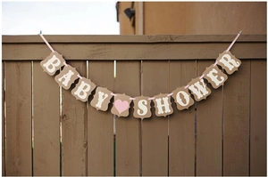 Close-up of vintage kraft cardstock Baby Shower banner with pink ribbon on wooden fence