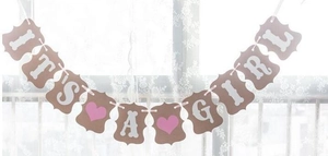 Detail of vintage kraft paper 'IT'S A GIRL' banner with pink hearts for baby party decoration