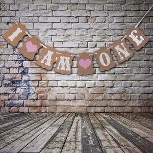 Close-up of I AM ONE kraft paper banner with pink hearts and bone designs for first birthday