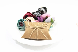 Close-up of kraft paper pillow gift box with natural jute rope bow on a white plate