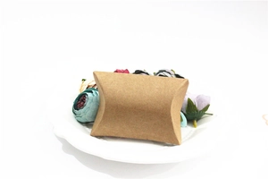 Brown kraft paper pillow box on a white tray with decorative flowers for gift packaging