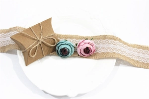 Detail of kraft pillow favor box with jute twine bow, lace ribbon, and faux flower decor
